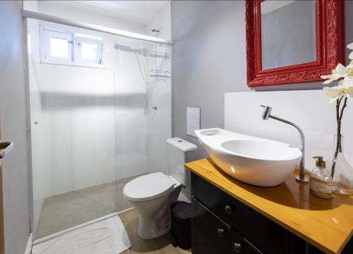 uma casa de banho com um lavatório, um WC e um espelho. em Loft Califórnia em Bombinhas