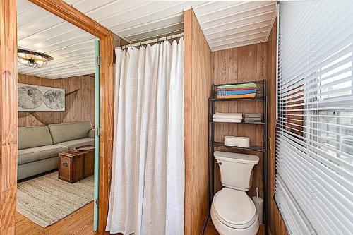 a small bathroom with a toilet and a couch at Shipwrecked Shack Waterfront House Boat on Land in Sealevel