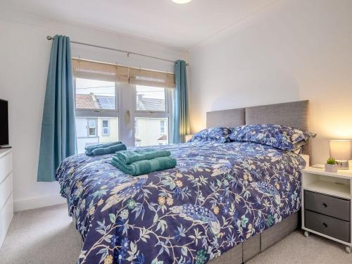 a bedroom with a bed with a blue comforter and a window at Newlands Nook in Weston-super-Mare