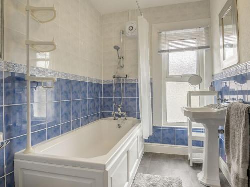 Newlands Nook في ويستون سوبر مير: حمام من البلاط الأزرق مع حوض استحمام ومغسلة