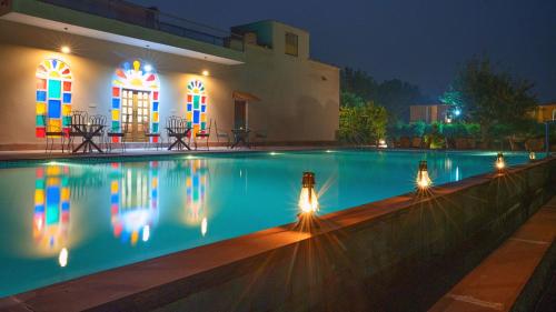 uma piscina em frente a uma casa à noite em Anantvan Ranthambore By Asapian Hotels em Khilchīpur