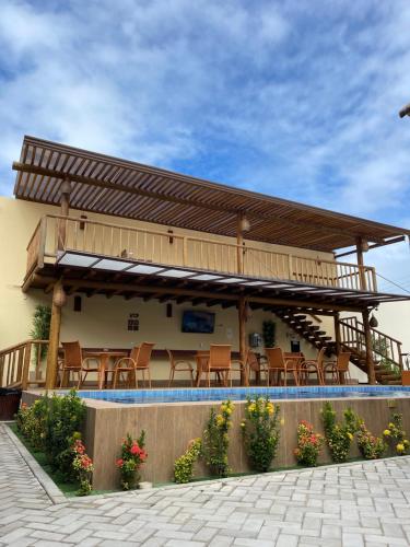 a building with a deck with chairs on it at Pousada Lua Nova Charmosa Pipa in Pipa
