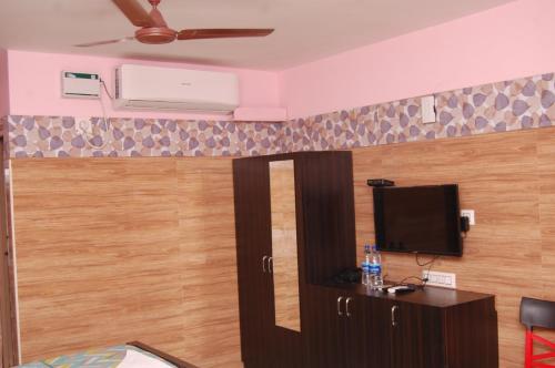 a room with a bed and a tv on a wall at Adhi Residency in Kanchipuram