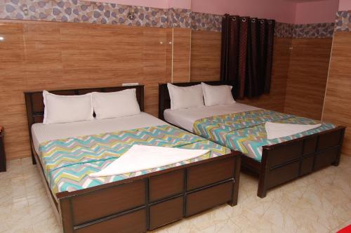 duas camas sentadas uma ao lado da outra num quarto em Adhi Residency em Kanchipuram