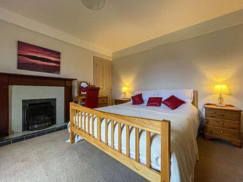 ein Schlafzimmer mit einem Bett mit roten Kissen und einem Kamin in der Unterkunft Milton Cottage in Invercassley