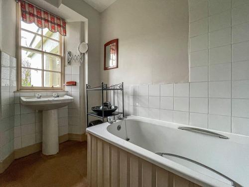 ein Badezimmer mit einer Badewanne und einem Waschbecken in der Unterkunft Milton Cottage in Invercassley