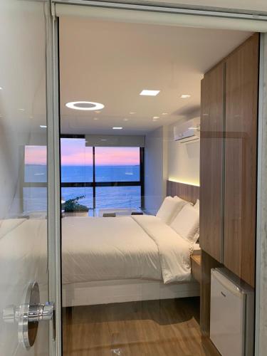 a bedroom with a bed and a view of the ocean at Hotel Espadarte in Iriri