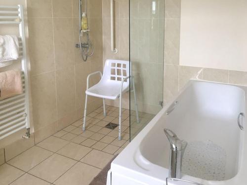 a bathroom with a white chair next to a bath tub at Lantonhall West Wing in Lanton