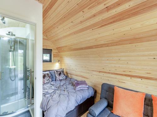 a bedroom with wooden walls and a bed and a shower at Chestnut-uk36261 in Llanfair Caereinion