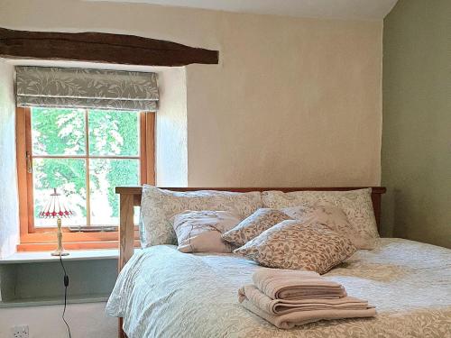 a bedroom with a bed with pillows and a window at Clematis Cottage in Penrith