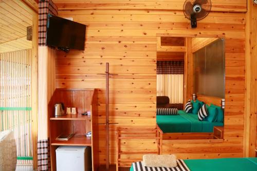 a bedroom with a green bed in a wooden wall at Ella Country House in Ella