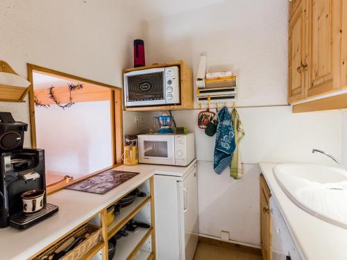 une petite cuisine avec un micro-ondes et un évier dans l'établissement Charmant T2 Montchavin La Plagne, 36m², balcon sud, proche pistes et commerces, parking gratuit - FR-1-329-83, à La Plagne Tarentaise