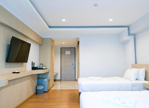 a hotel room with two beds and a flat screen tv at Sann Hotel in Chiang Rai