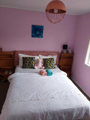 a teddy bear laying on a bed in a bedroom at Wendy's Holiday Home in Auckland