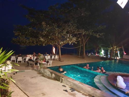 a group of people sitting in a swimming pool at night at Baan Ampai Beach Hotel in Hua Thanon Beach