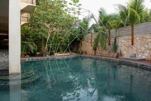 a swimming pool in a backyard with a stone wall at Botånica Tulum in Tulum