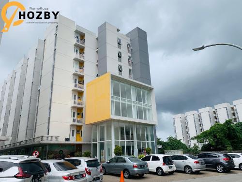 een parkeerplaats met auto's voor een gebouw bij Hozby Suites Aeropolis Premier in Teko