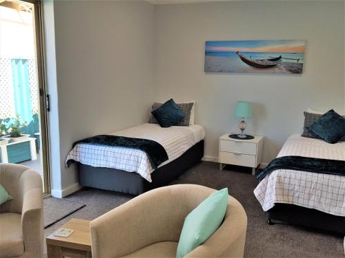 ロッキンガムにあるPalm Beach Guest Houseのベッド2台、ソファ、椅子が備わる客室です。