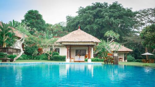 a villa with a swimming pool in front of a house at The Lotus Residence by Amerta Experience in Tabanan