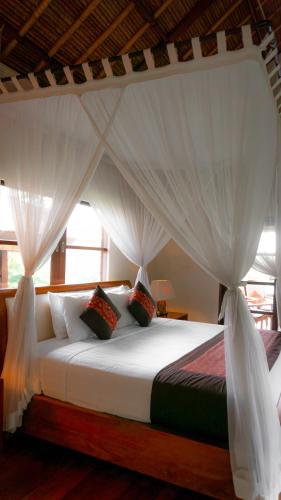 a bedroom with a canopy bed with white curtains at The Lotus Residence by Amerta Experience in Tabanan