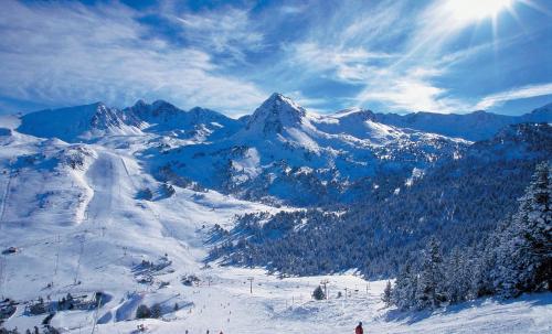 a snow covered mountain with the sun shining on at Hotel Merino in Pas de la Casa