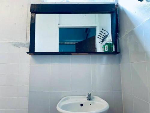 a bathroom with a sink and a mirror on the wall at Blissful Cottage in Pantai Cenang