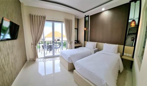 デンパサールにあるUltimate Residence Baliのベッド2台とバルコニーが備わるホテルルームです。