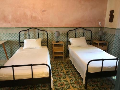 two beds in a room with two tables and two lamps at Casa Nicté, hospédate en una casa del siglo XVIII in Campeche