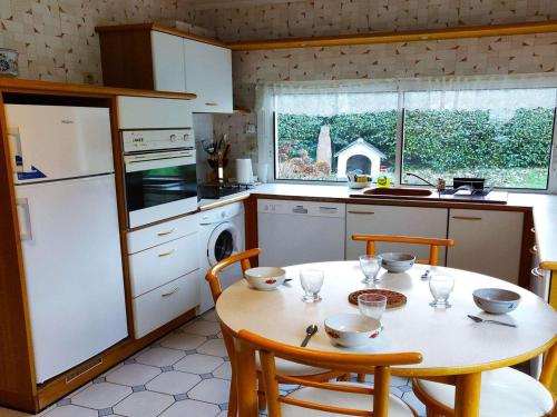 Il comprend une cuisine équipée d'une table avec des chaises et d'un réfrigérateur blanc. dans l'établissement Maison rustique à 100m de la mer, 6 pers, jardin, Wi-Fi, parking, animaux OK, Côte de Granit Rose - FR-1-542-15, à Trégastel
