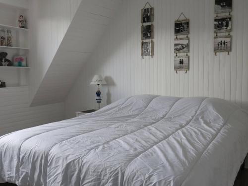 a white bed in a white bedroom with pictures on the wall at Maison de charme 3* avec WIFI, jardin clos, véranda, à 350m du port à Perros-Guirec - FR-1-368-254 in Perros-Guirec