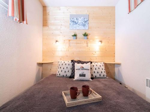 une chambre avec un lit avec deux tasses sur un plateau dans l'établissement Appartement calme 4 pers avec balcon et parking, près centre Saint-Lary - FR-1-296-331, à Saint-Lary-Soulan