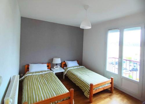 une chambre avec deux lits et une fenêtre dans l'établissement Appartement 76m2 lumineux centre ville garage privé 3ieme étage sans ascenseur, à Fougères