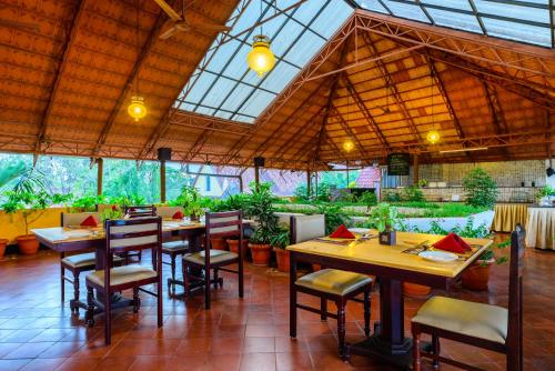 un restaurante con mesas de madera, sillas y plantas en Hotel Arches, en Kochi