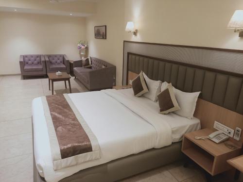 a bedroom with a large bed and a living room at Rudra Shelter Business Hotel in Vasai