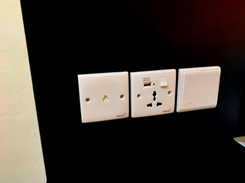 three switches on a wall with a black wall at Newly Built Apartment Studio Nagoya Thamrin City Blok A in Nagoya