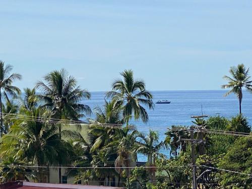 a view of the ocean with palm trees and a boat at Da Kona West 305 in Kailua-Kona
