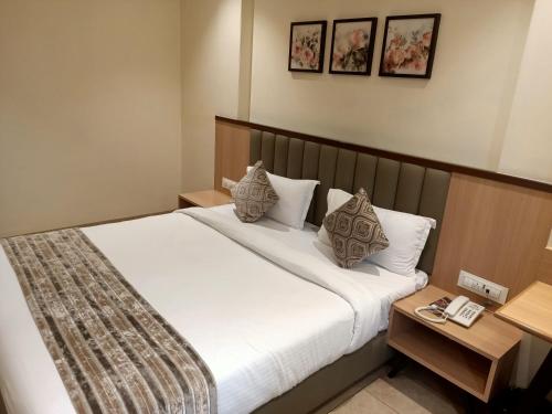 1 dormitorio con 1 cama con sábanas y almohadas blancas en Rudra Shelter Business Hotel en Vasai