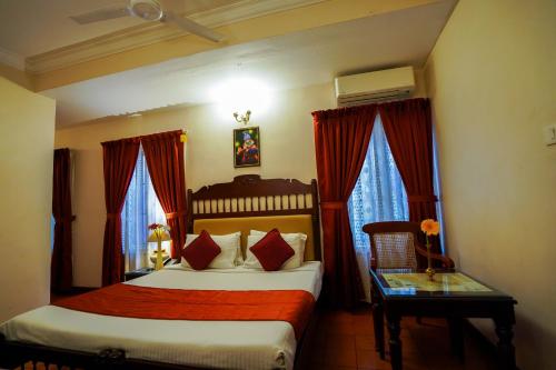 a bedroom with two beds and red curtains at Hotel Arches in Cochin