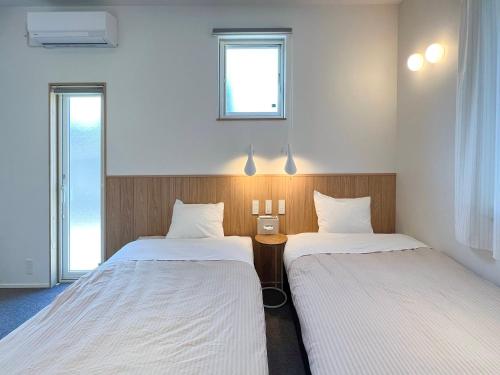 2 Betten in einem Zimmer mit 2 Fenstern in der Unterkunft Beach SPA TSUDA 0 Cero棟 in Sanuki