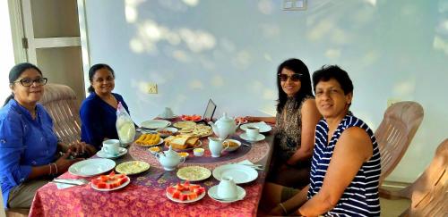 a group of people sitting around a table with food at Poomaz Peace Palace in Ella