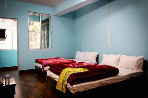 SHARTHI HOMESTAY AND LODGING في Namchi: سرير كبير في غرفة ذات جدار ازرق