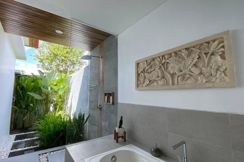 a bathroom with a bath tub and a large window at Nau Nusa Villa in Nusa Penida
