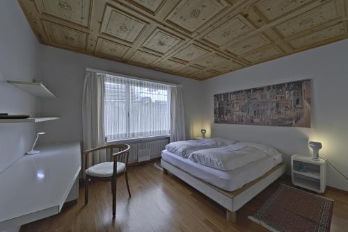 a bedroom with a bed and a desk and a window at Allod Brattas - Sankt Moritz in St. Moritz