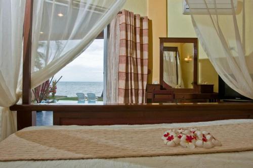 a bedroom with a bed with a view of the ocean at Crystal Paradise Resort Spa & Winery in Narra