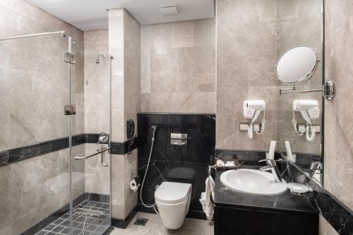 a bathroom with a toilet and a sink and a shower at Roots Hotel in Makkah