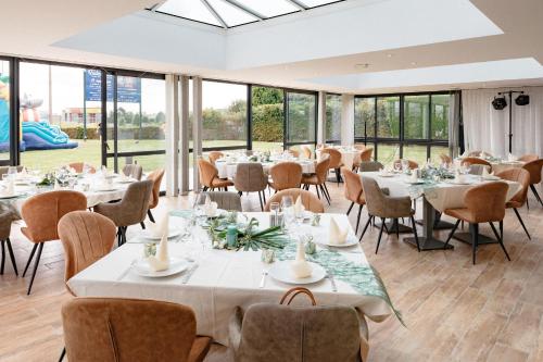 uma sala de jantar com mesas, cadeiras e janelas em Le Pavillon de Rouen em Franqueville-Saint-Pierre