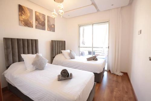 - 2 lits dans une chambre avec fenêtre dans l'établissement APPARTEMENT RIAD WHITE GOLDEN, à Marrakech