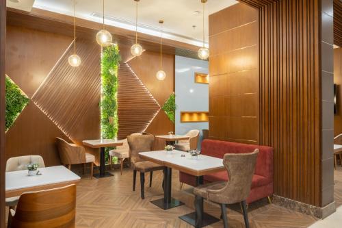 a restaurant with tables and chairs and a red couch at Roots Hotel in Makkah