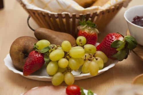 a plate of fruit on a table with a basket of strawberries at Bellevue Budapest B&B in Budapest