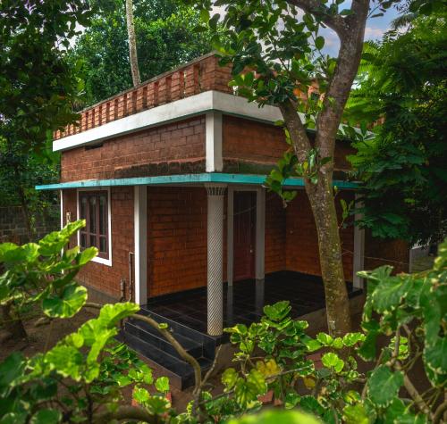 ein rotes Backsteinhaus mit einer Veranda und einem Baum in der Unterkunft Secret Paradise in Varkala